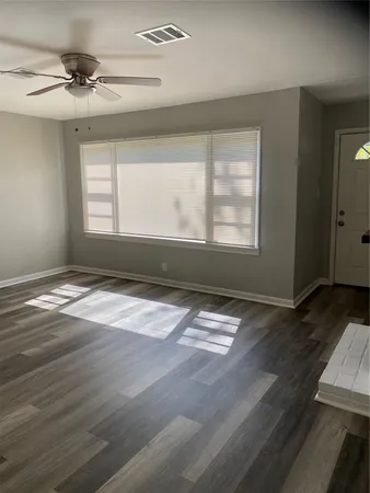 an empty room with wooden floor and windows