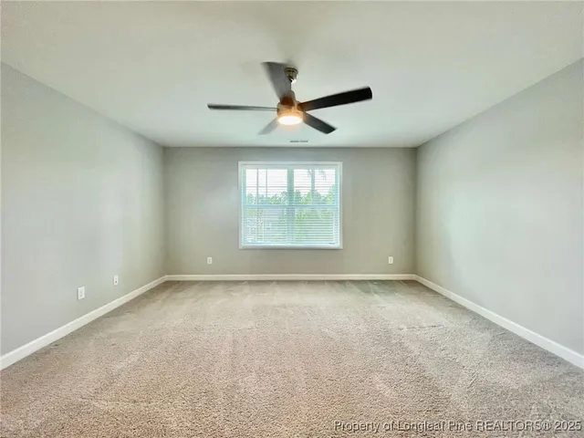 an empty room with a window and a ceiling fan