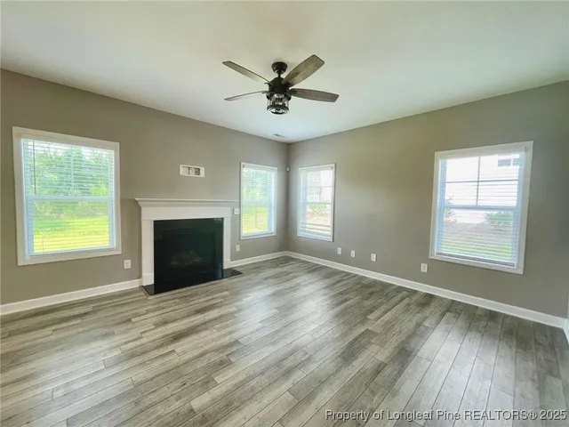 an empty room with windows and fireplace