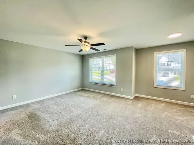 an empty room with windows and chandelier fan