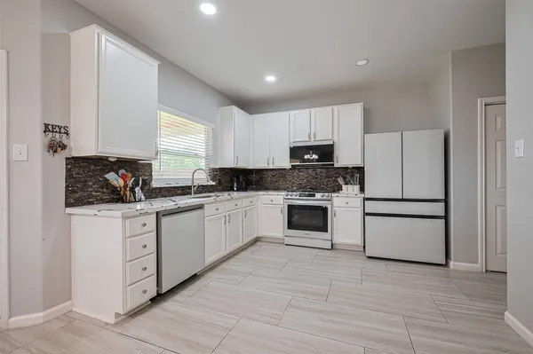 a kitchen with granite countertop white cabinets and white appliances