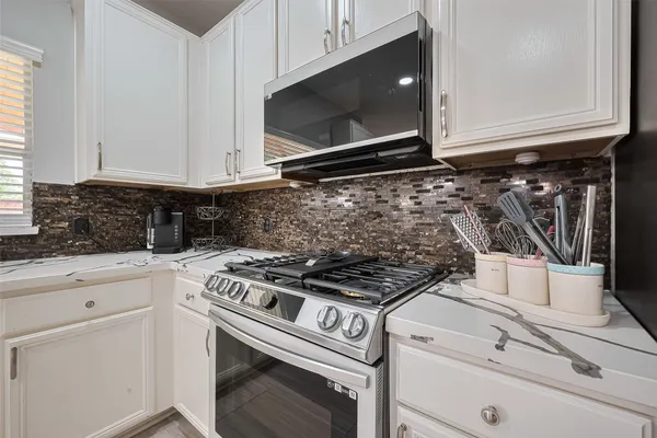 a kitchen with white cabinets and appliances
