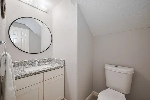 a bathroom with a granite countertop toilet a sink and a mirror