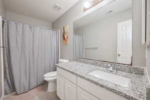a bathroom with a granite countertop sink and a mirror with toilet