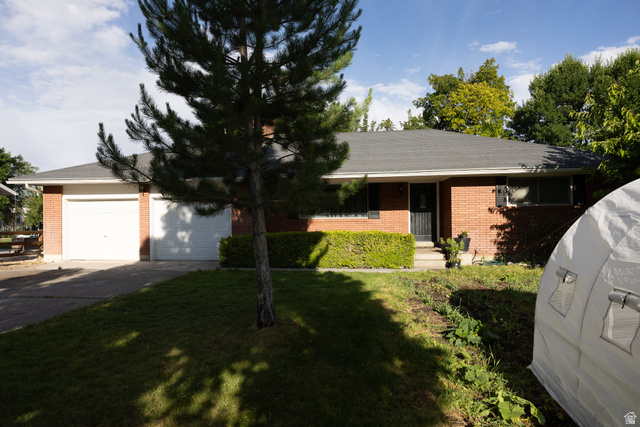 827 South 600 East Logan, UT 84321 - Photo 1 of 30 Brick exterior residence featuring a two-car garage, mature front yard tree, manicured shrubbery, and a paved driveway