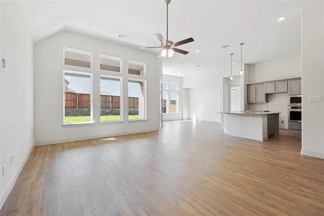 a view of an empty room with a kitchen and wooden floor