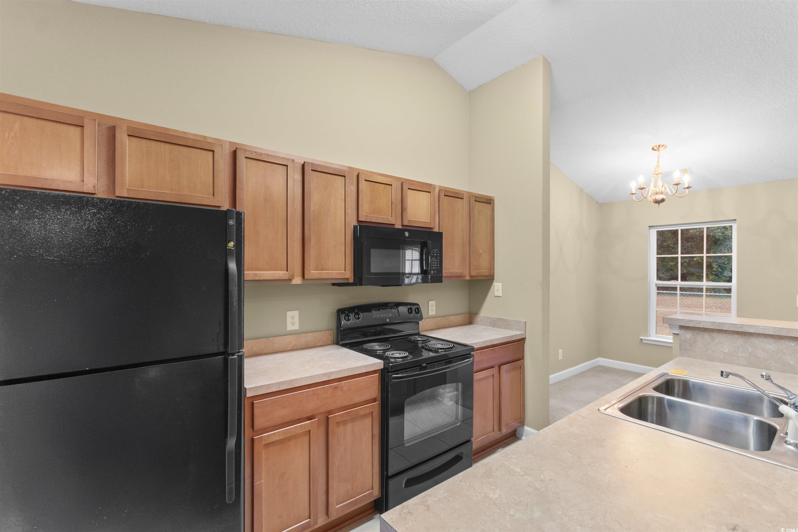 85 Graham Road Georgetown, SC 29440 - Photo 11 of 39 Kitchen featuring black appliances, light countertops, a chandelier, vaulted ceiling, and hanging light fixtures
