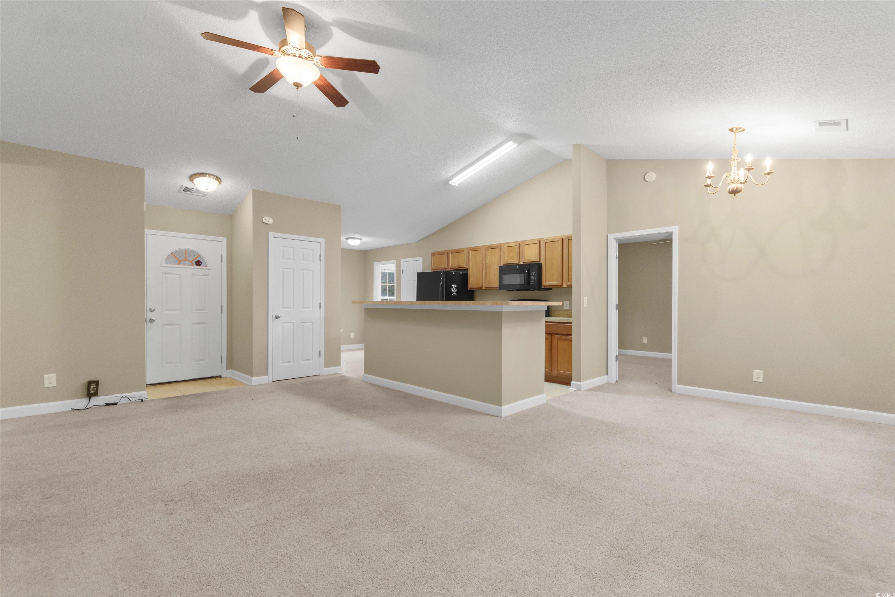 85 Graham Road Georgetown, SC 29440 - Photo 4 of 39 Unfurnished living room featuring light colored carpet, a ceiling fan, vaulted ceiling, and a chandelier