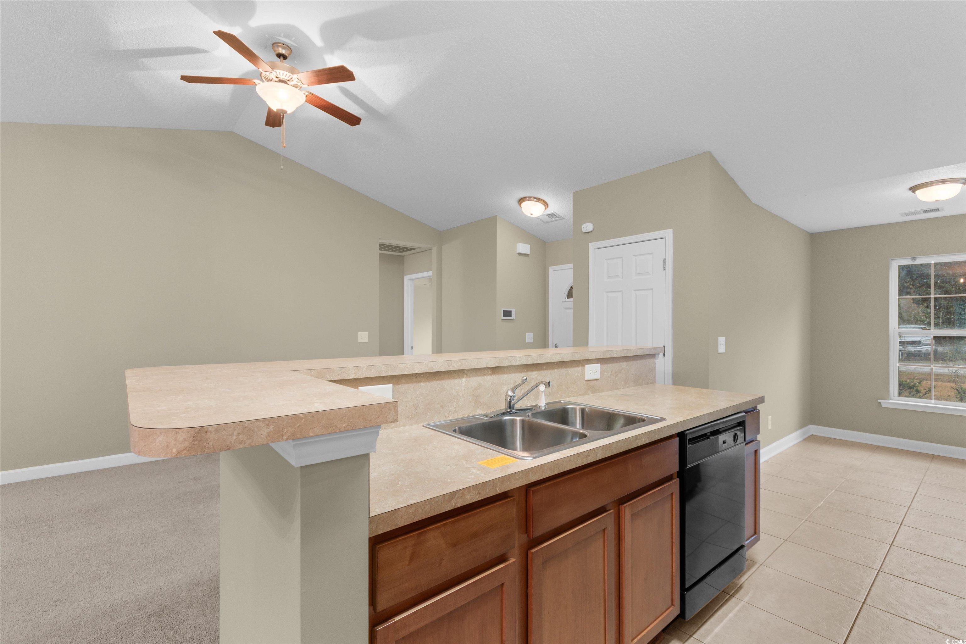85 Graham Road Georgetown, SC 29440 - Photo 9 of 39 Kitchen featuring light countertops, a kitchen island with sink, dishwasher, brown cabinets, and vaulted ceiling