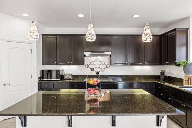 a kitchen with kitchen island granite countertop a stove a sink and dishwasher wooden cabinets with granite countertops