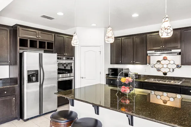 a kitchen with stainless steel appliances granite countertop a refrigerator and a stove