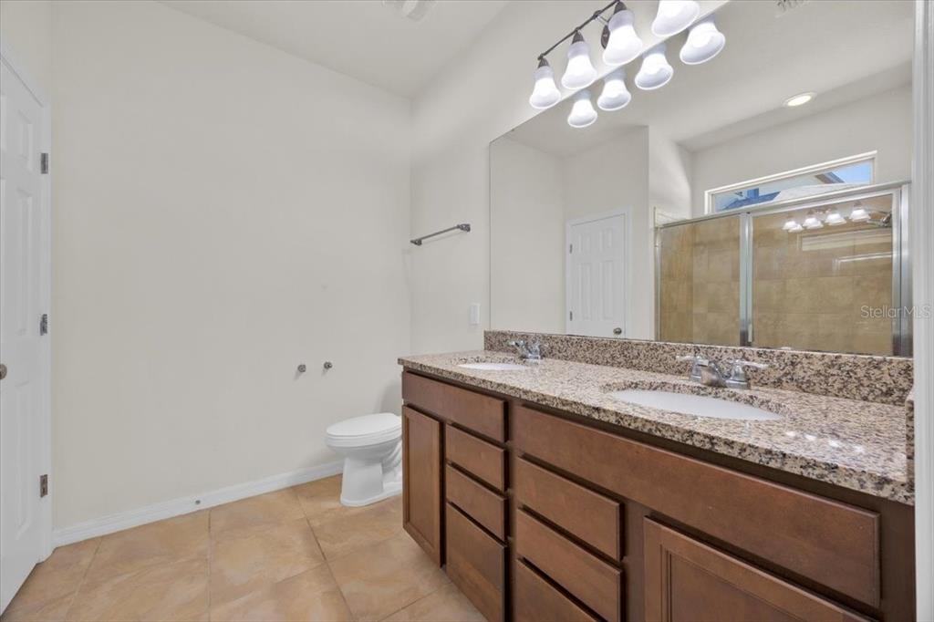8755 Rindge Road Polk City, FL 33868 - Photo 14 of 25 a bathroom with a granite countertop sink a toilet and a mirror