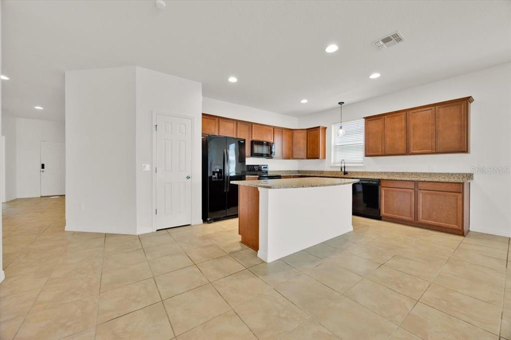 8755 Rindge Road Polk City, FL 33868 - Photo 9 of 25 a large kitchen with stainless steel appliances granite countertop a stove top oven a sink and a refrigerator