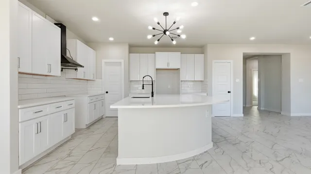 a large white kitchen with kitchen island a sink stainless steel appliances and cabinets
