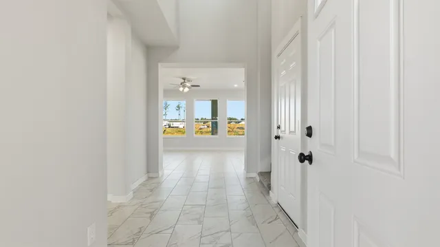 a view of a hallway with wooden floor and a bathroom