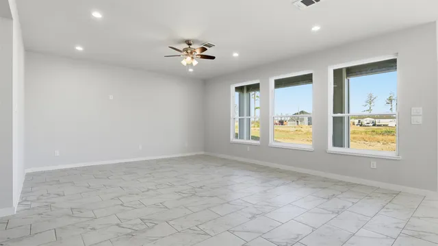 an empty room with windows and chandelier fan
