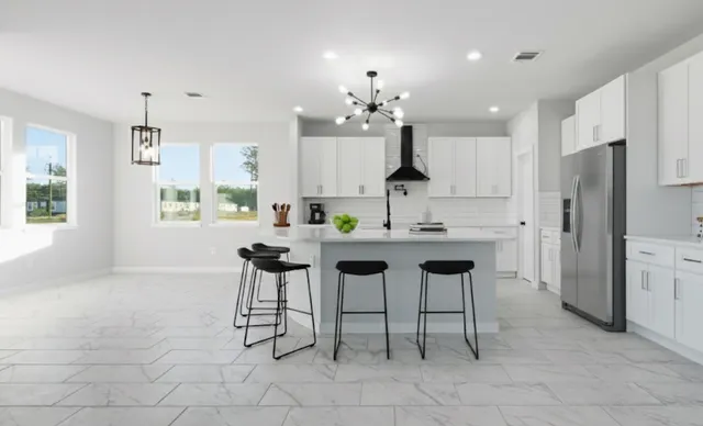 a kitchen with stainless steel appliances kitchen island granite countertop a sink and a refrigerator