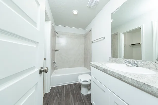 a bathroom with a granite countertop toilet a sink and a bathtub
