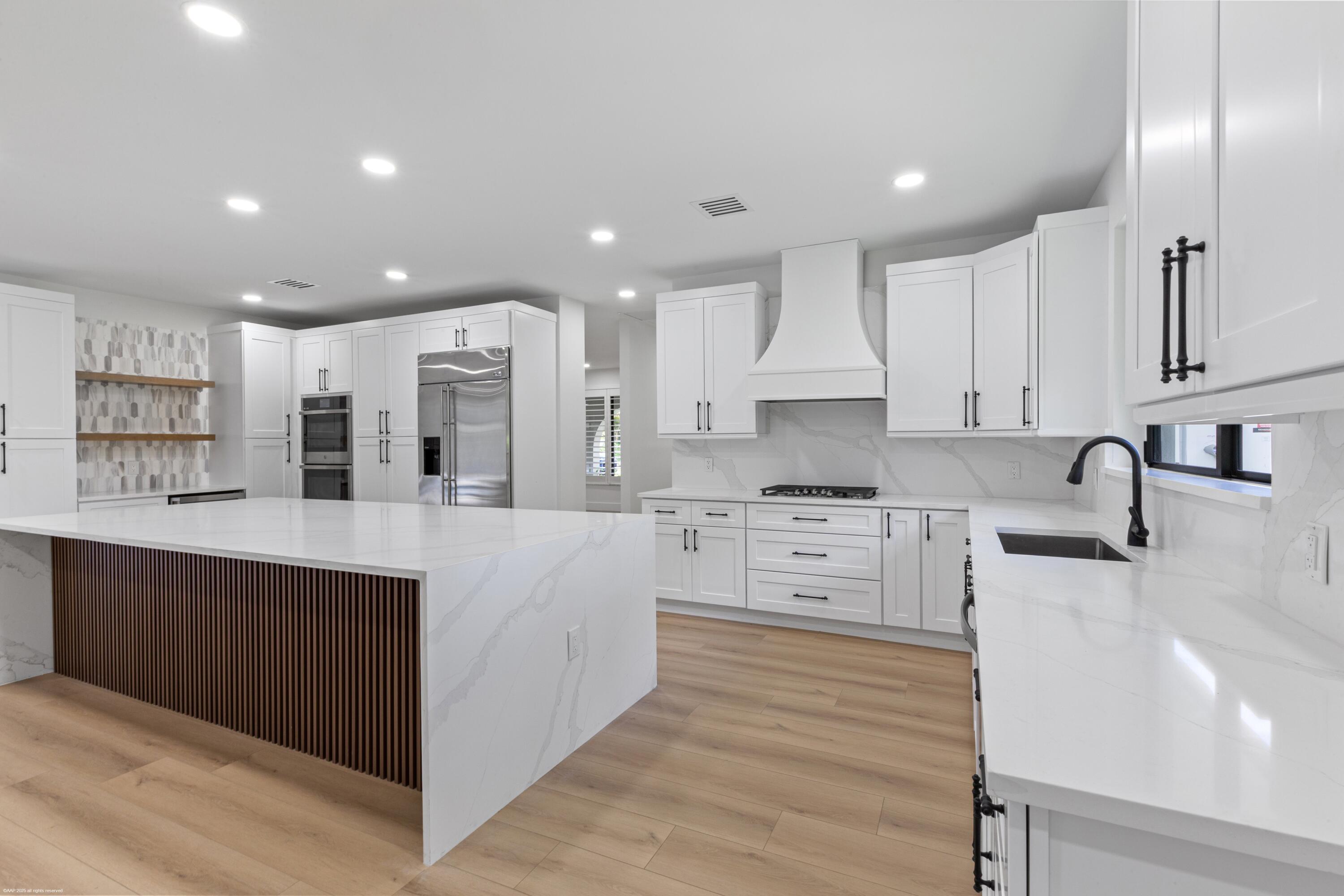 13453 Doubletree Trail Wellington, FL 33414 - Photo 19 of 65 a large kitchen with stainless steel appliances granite countertop a lot of counter space and wooden floors