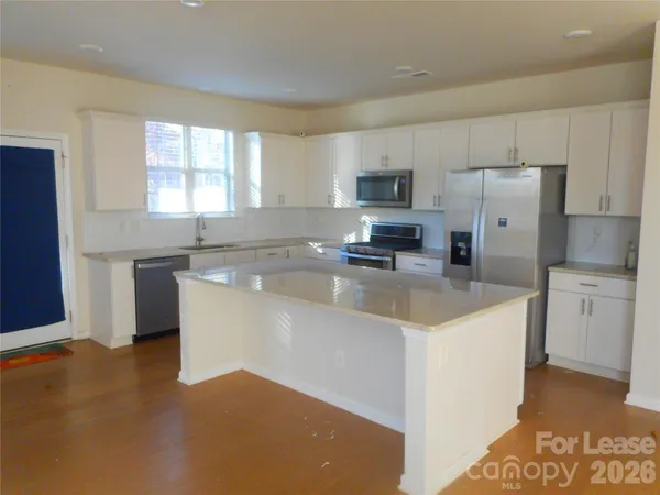 a kitchen with stainless steel appliances granite countertop a stove a sink a refrigerator a microwave and cabinets