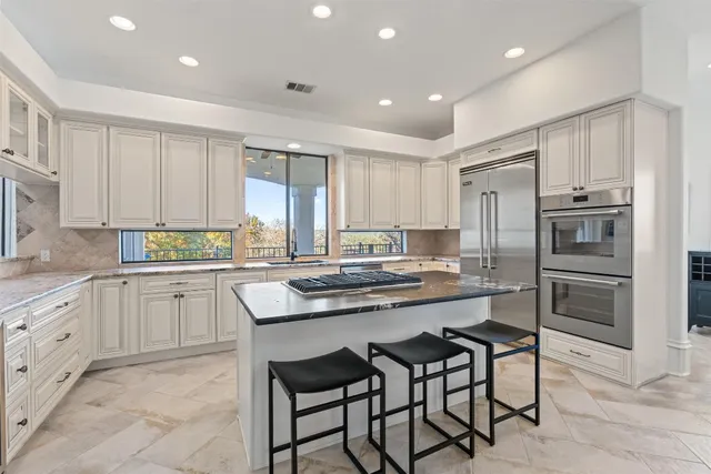 a kitchen with kitchen island white cabinets and stainless steel appliances