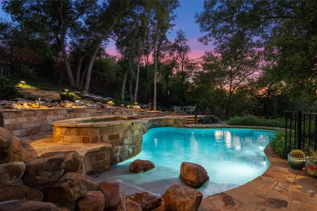 a view of a swimming pool with a patio and fire pit