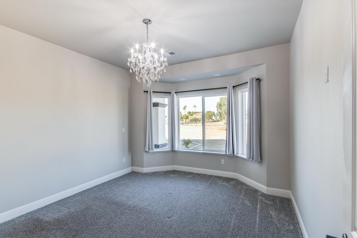 16639 Mark Road Madera, CA 93636 - Photo 15 of 33 an empty room with a chandelier fan and windows