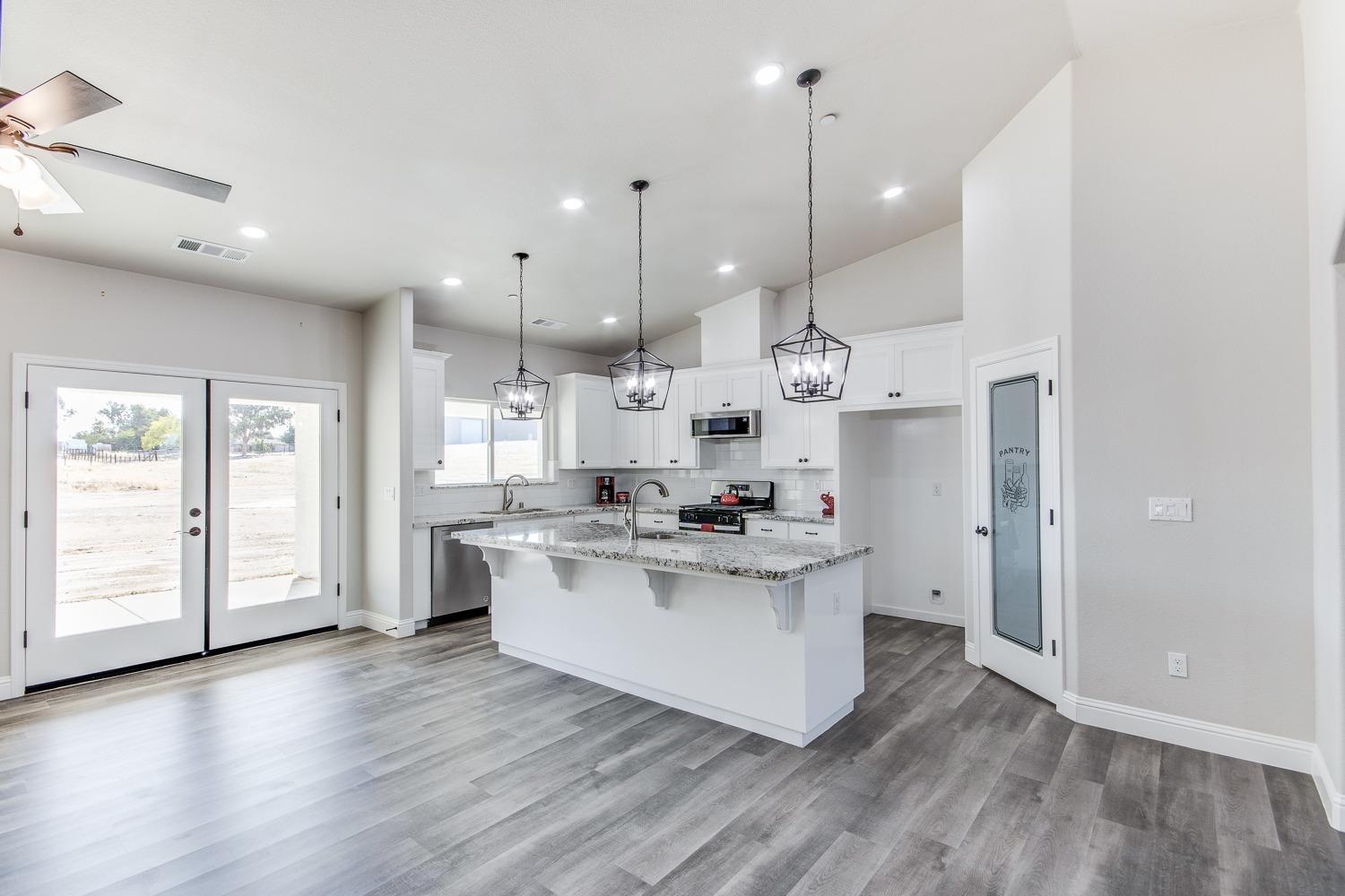 16639 Mark Road Madera, CA 93636 - Photo 6 of 33 a kitchen with stainless steel appliances kitchen island a white cabinets and wooden floor