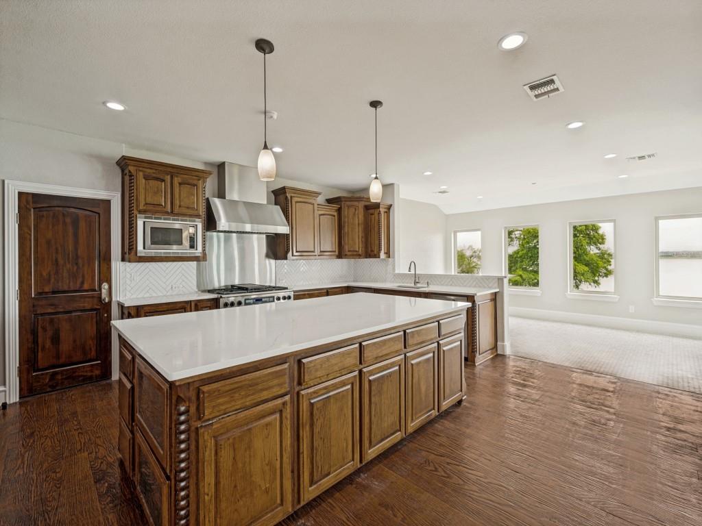 5975 Diamond Spur Frisco, TX 75036 - Photo 12 of 40 a kitchen with kitchen island a stove a sink a center island and wooden floor