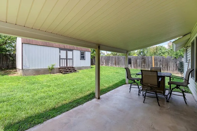 a view of a patio with table and chairs under an umbrella