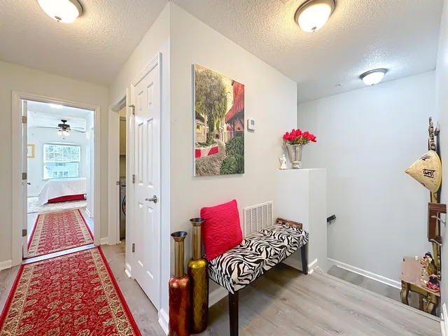 a view of a hallway with bed and wooden floor