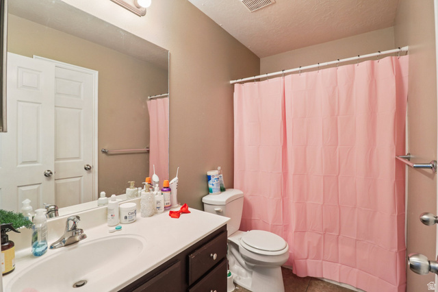 1077 South 1850th Street West Springville, UT 84663 - Photo 17 of 22 Bathroom with vanity, a textured ceiling, shower / tub combo with curtain, and dark tile patterned flooring