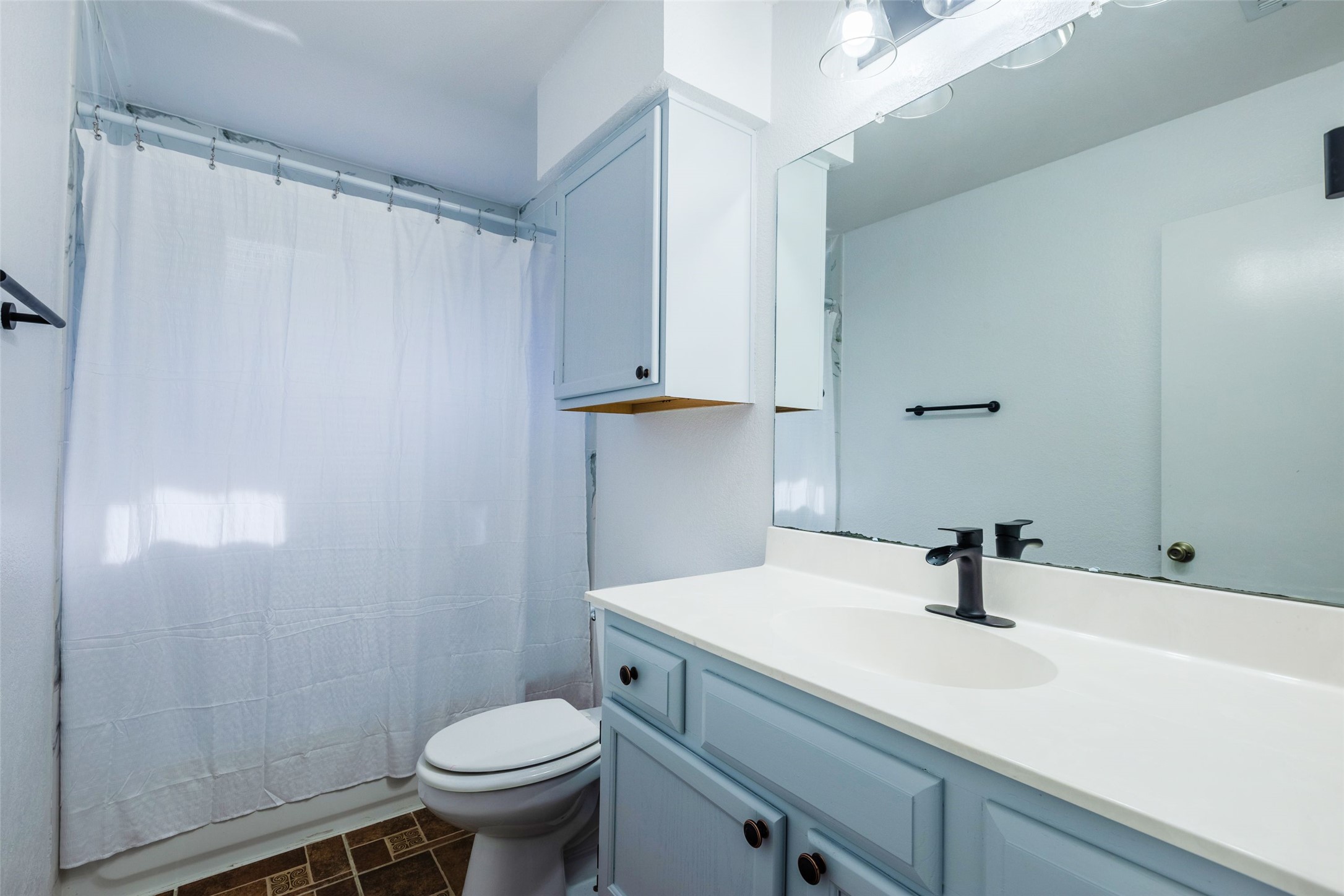 8506 Bisbee Court Austin, TX 78745 - Photo 11 of 20 Bathroom featuring a vanity with a white countertop and light blue cabinetry, a rectangular mirror, and a modern black faucet