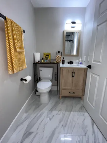 a bathroom with a granite countertop toilet sink and mirror