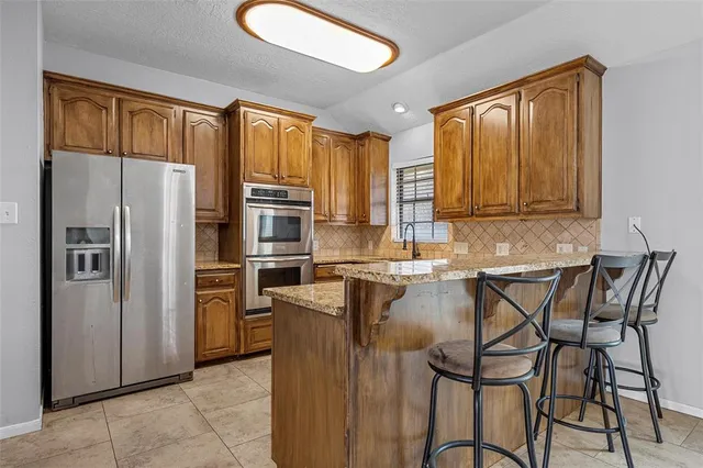 a kitchen with stainless steel appliances granite countertop a refrigerator a stove top oven and sink