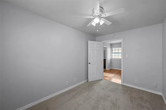 an empty room with a chandelier fan and a window