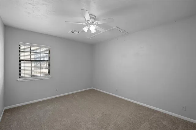 an empty room with a chandelier fan and windows