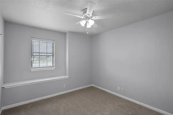 an empty room with a window and a ceiling fan