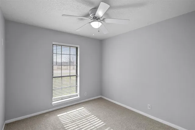 an empty room with windows and fan