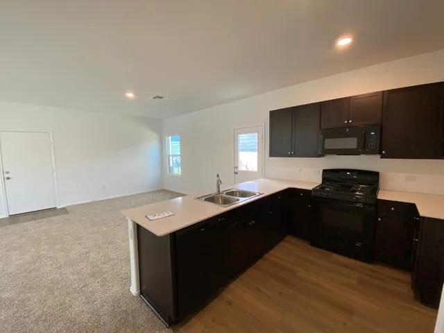 a kitchen with a sink and a stove top oven with wooden floor
