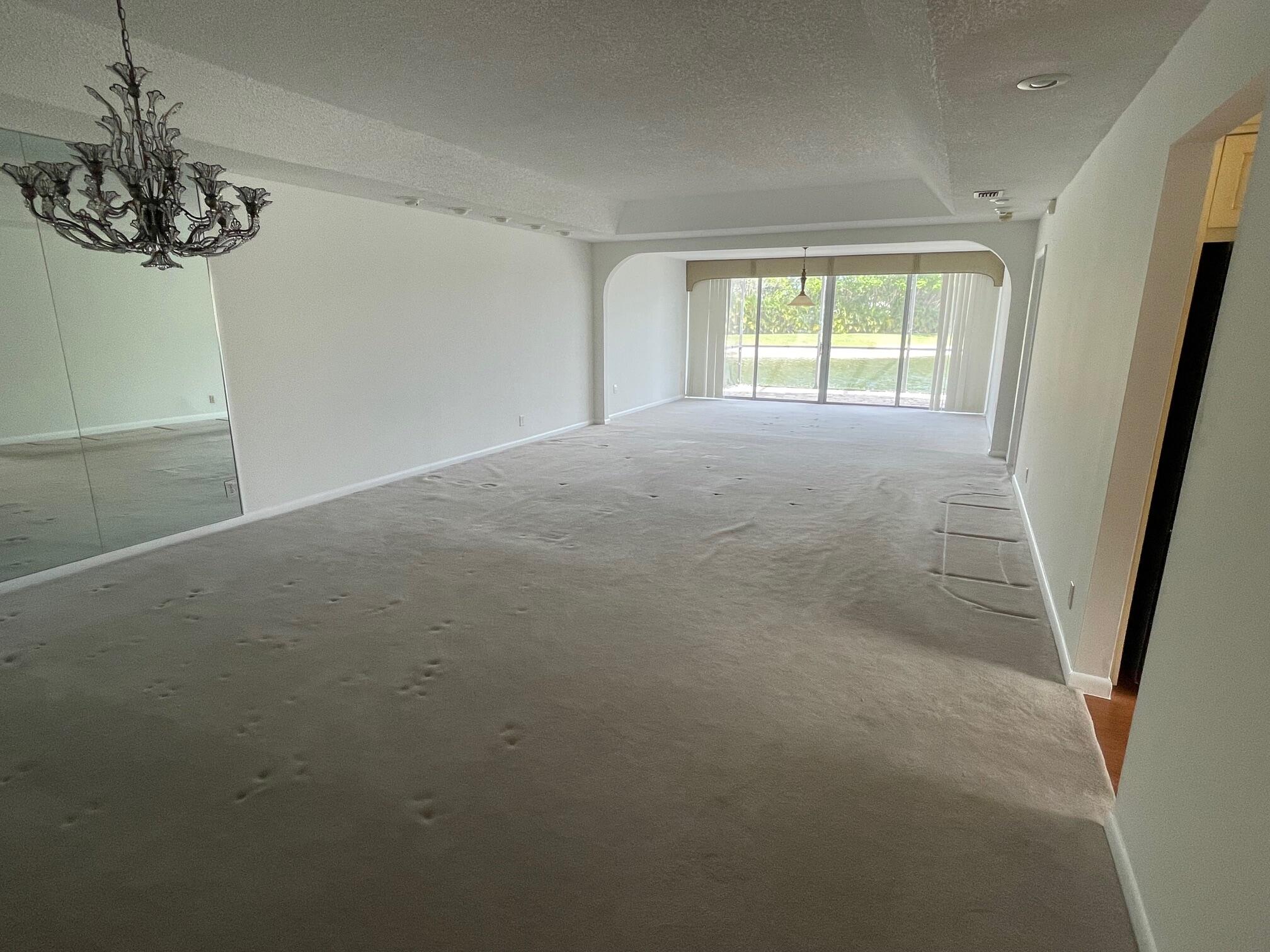 9151 Pine Springs Drive Boca Raton, FL 33428 - Photo 9 of 21 en empty room with windows and chandelier
