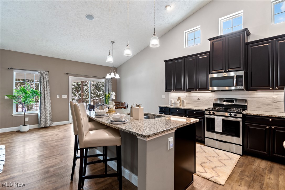191 Ry Road Wadsworth, OH 44281 - Photo 9 of 34 Kitchen featuring stainless steel appliances, light stone countertops, hanging light fixtures, tasteful backsplash, and a kitchen breakfast bar
