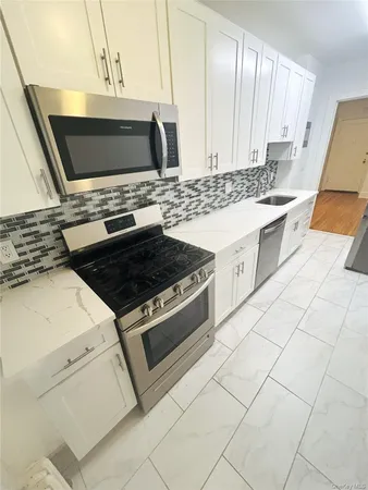 a kitchen with granite countertop a stove a sink and a microwave