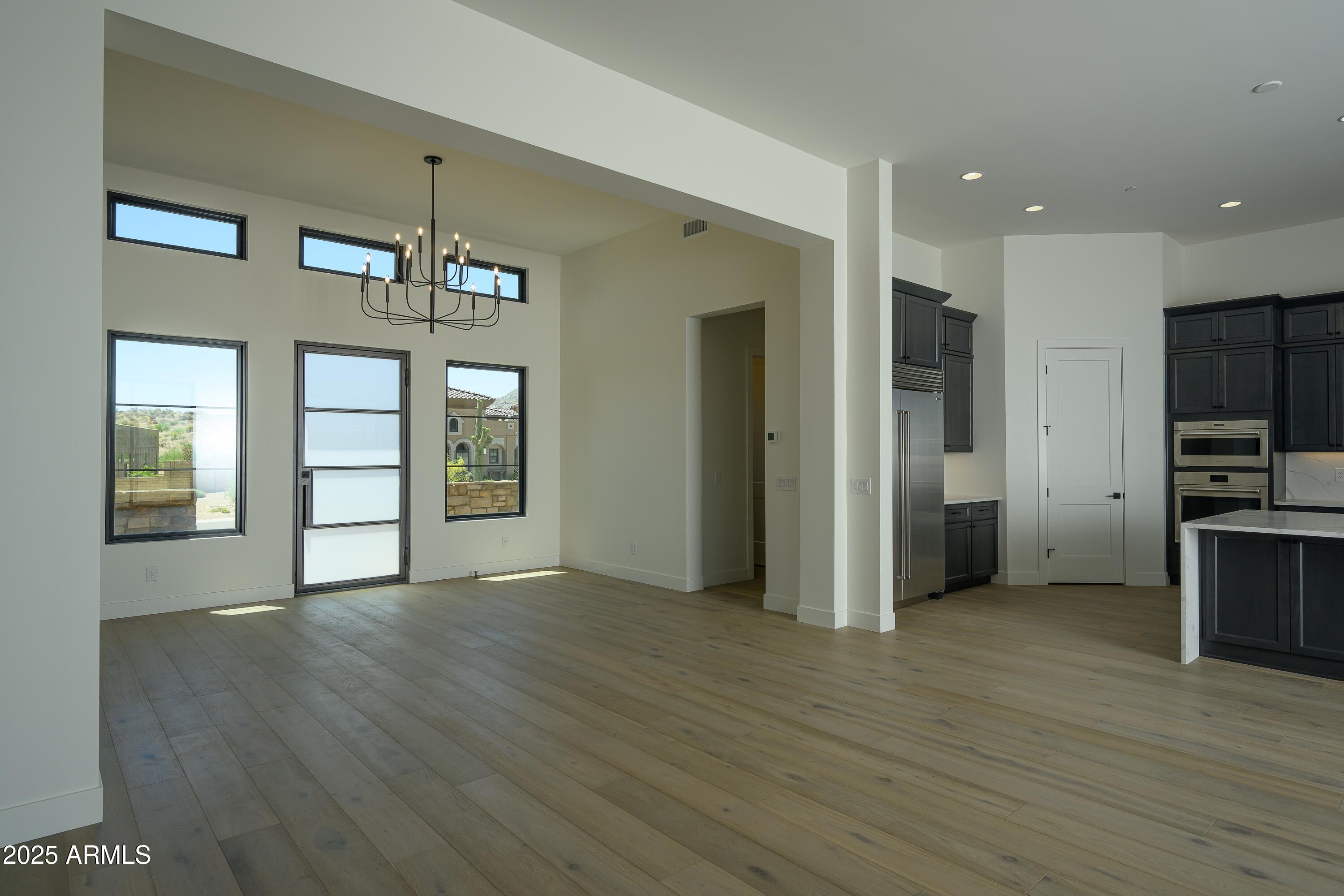 13290 East La Junta Road Scottsdale, AZ 85255 - Photo 3 of 15 an empty room with wooden floor chandelier and windows