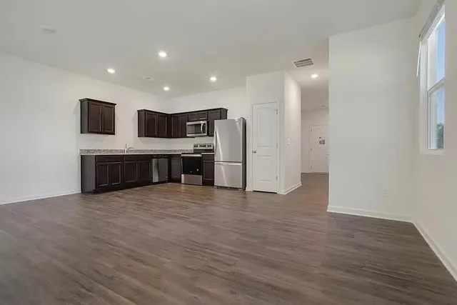 a view of a kitchen with a refrigerator a stove top oven and wooden floor