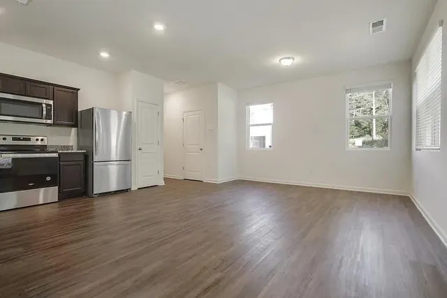 a kitchen with stainless steel appliances granite countertop a refrigerator a sink dishwasher a stove with wooden cabinets and floor