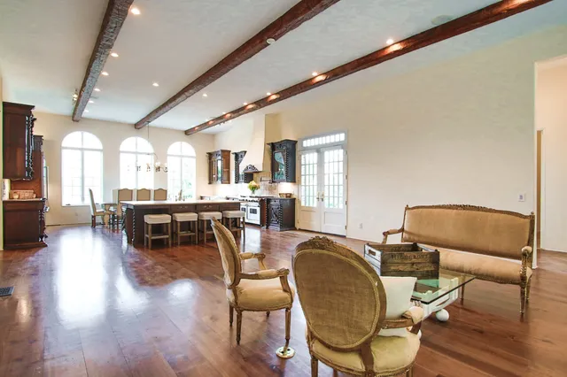 a living room with couches chairs and kitchen view with wooden floor