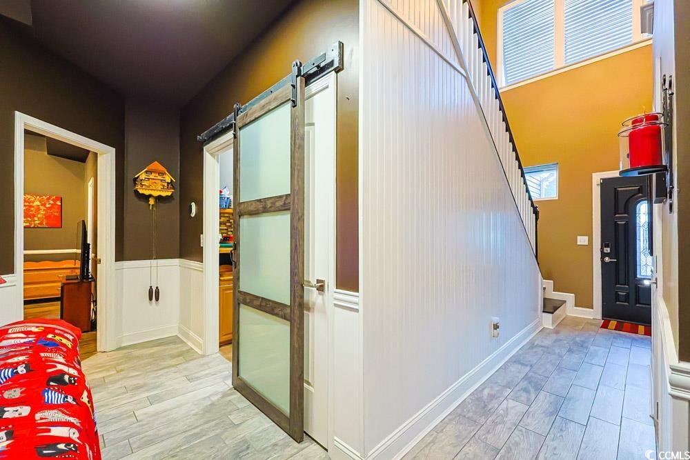105 Rocko Drive Myrtle Beach, SC 29579 - Photo 11 of 38 Hallway featuring a barn door, light wood-style flooring, and stairs