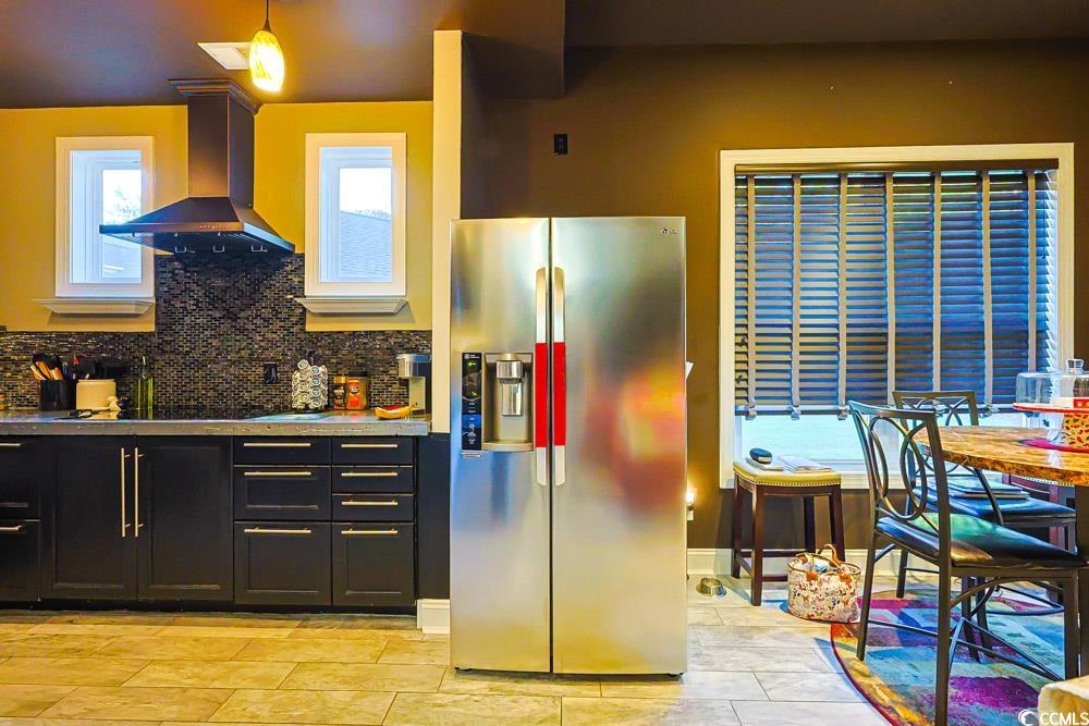 105 Rocko Drive Myrtle Beach, SC 29579 - Photo 5 of 38 Kitchen with dark cabinetry, stainless steel fridge with ice dispenser, wall chimney range hood, decorative backsplash, and light stone countertops