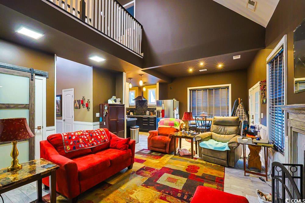 105 Rocko Drive Myrtle Beach, SC 29579 - Photo 9 of 38 Living room featuring light wood-style flooring, a barn door, a fireplace, and a high ceiling